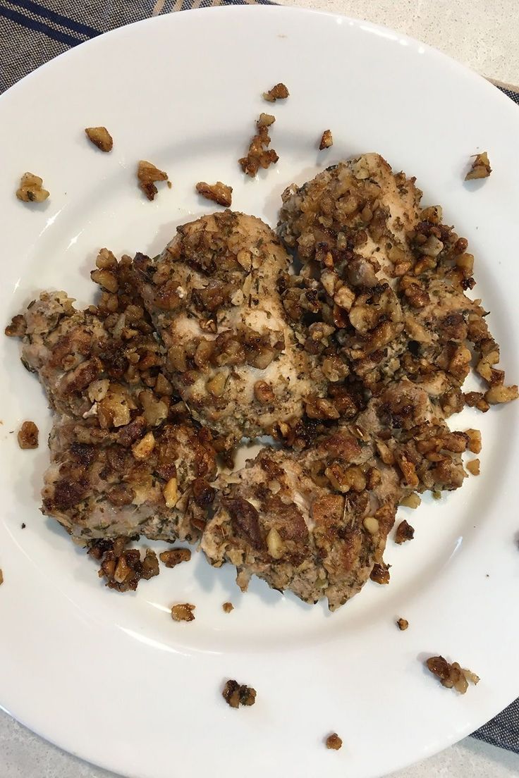 three pieces of meat on a white plate with crumbs all over the place