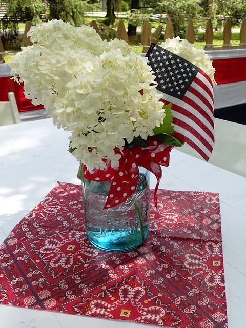 a vase filled with white flowers sitting on top of a red and white table cloth