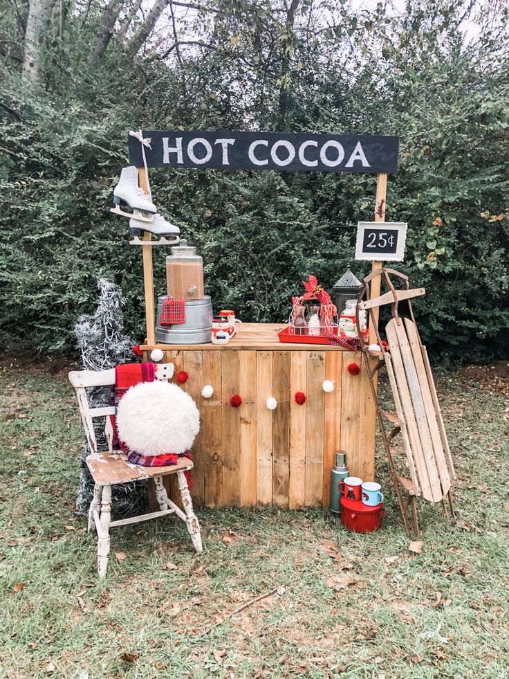 an outdoor hot cocoa stand with christmas decorations on the table and other items around it