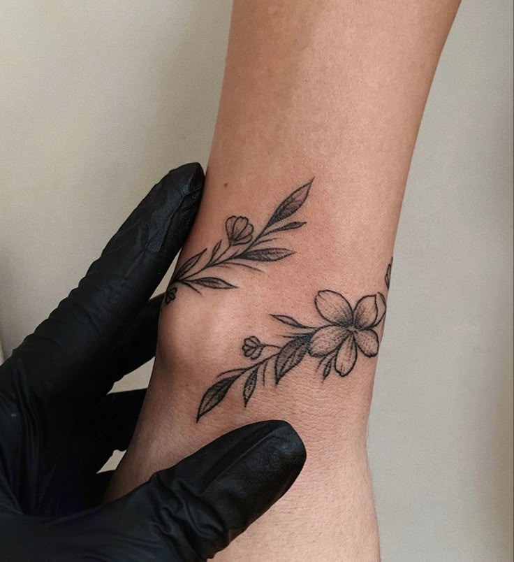 a woman's foot with flowers on it and a black glove next to her