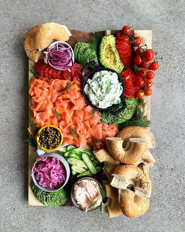 a wooden cutting board topped with different types of foods and vegetables on top of each other