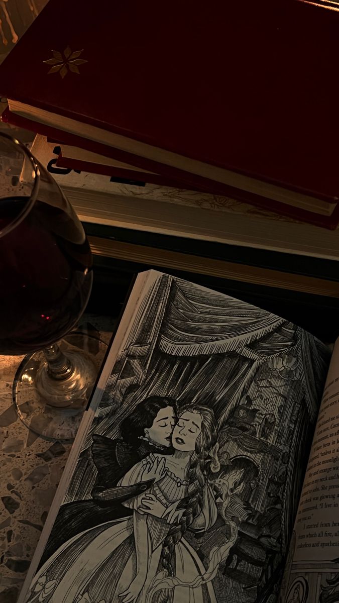 an open book sitting on top of a table next to a glass of wine