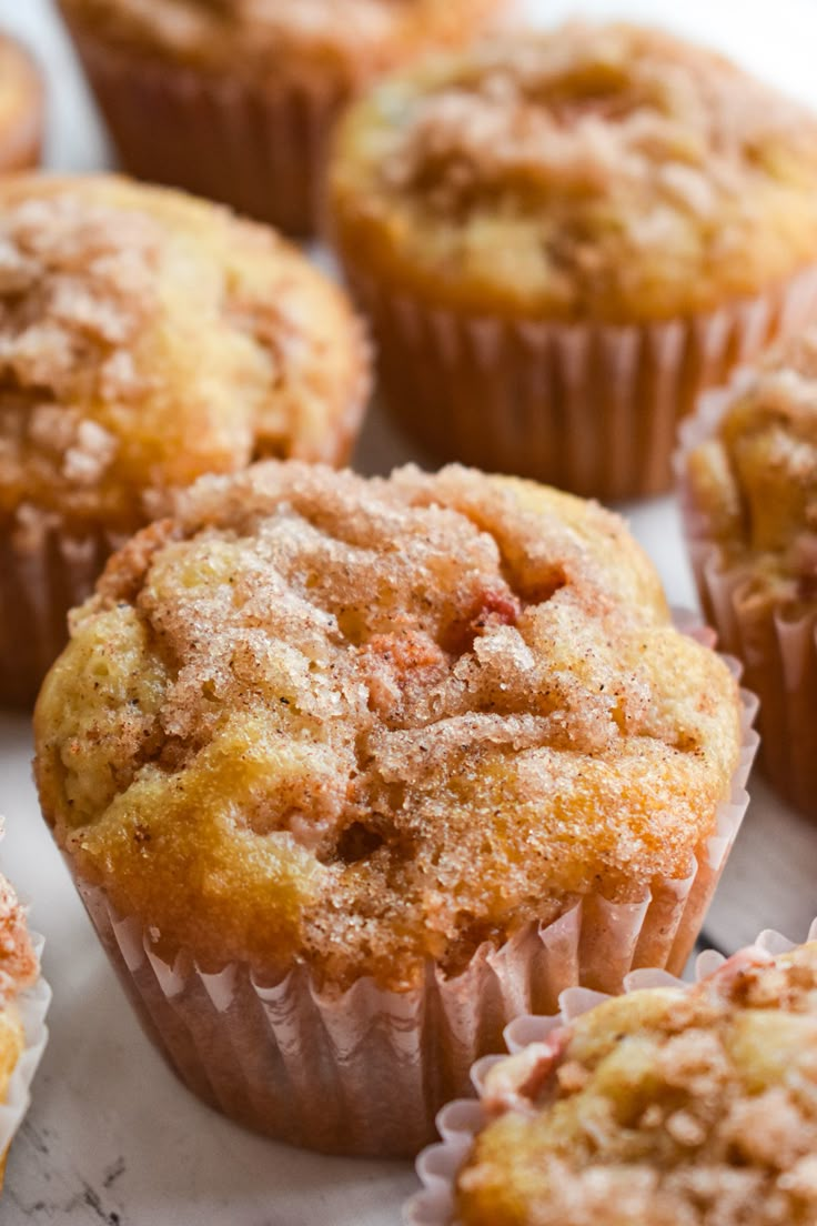 muffins with powdered sugar on top sitting on a white surface, ready to be eaten