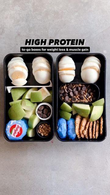 two black trays filled with food on top of a cement floor next to each other