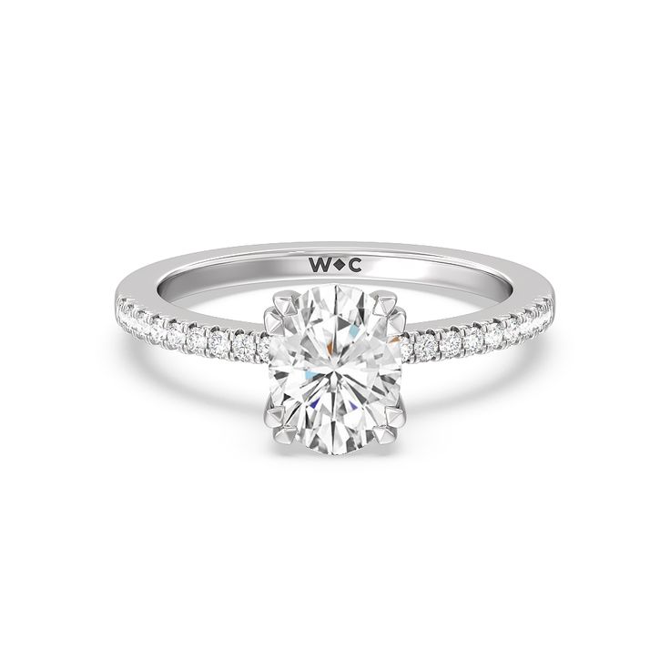 a white gold engagement ring with diamonds on the band and a round cut diamond in the center