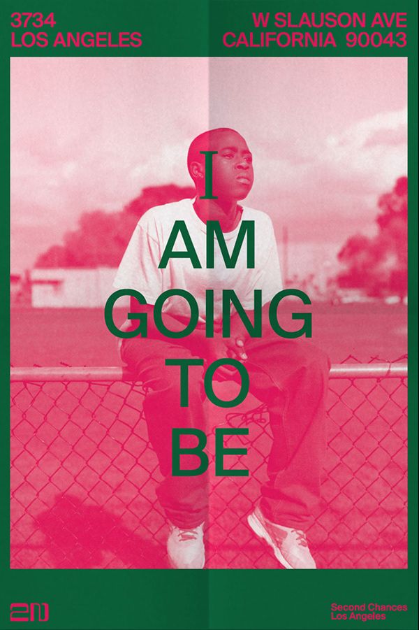 a man sitting on top of a fence next to a red and green poster with the words i am going to be