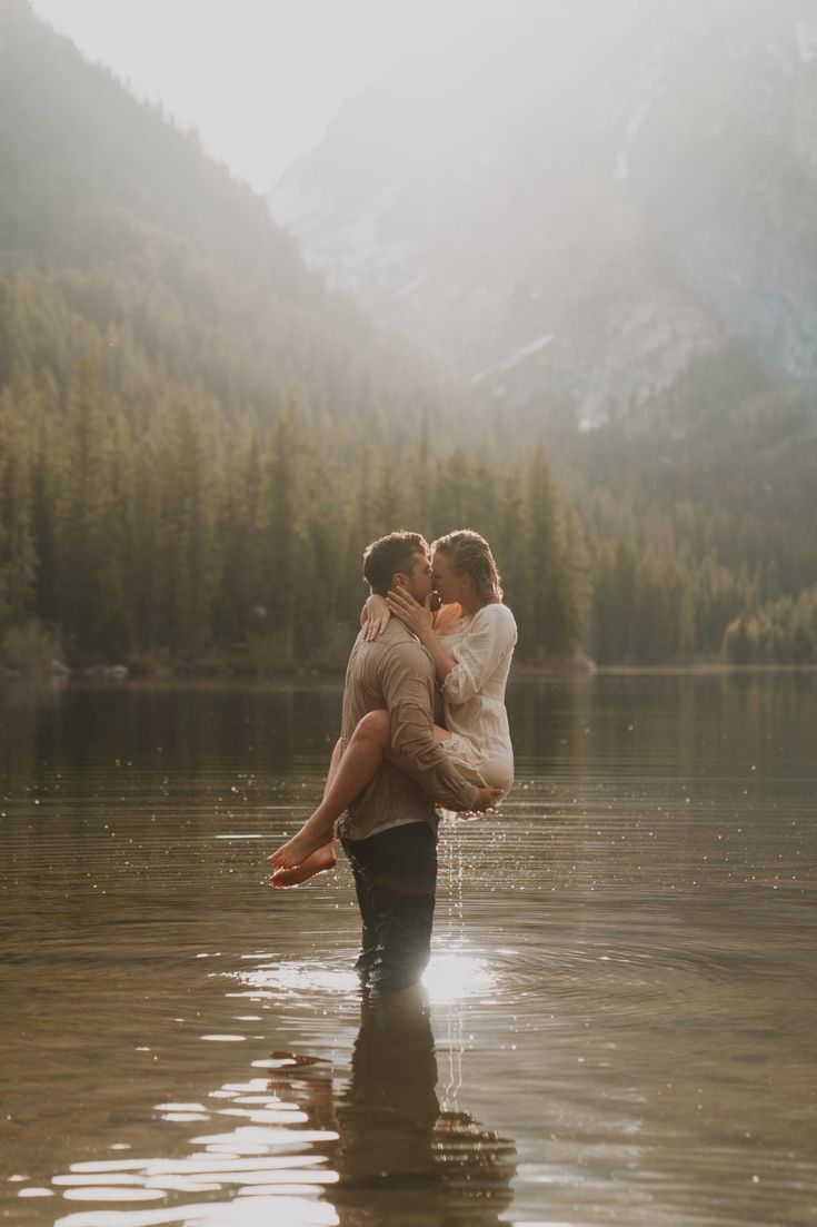 a man and woman are standing in the water with their arms around each other as they kiss