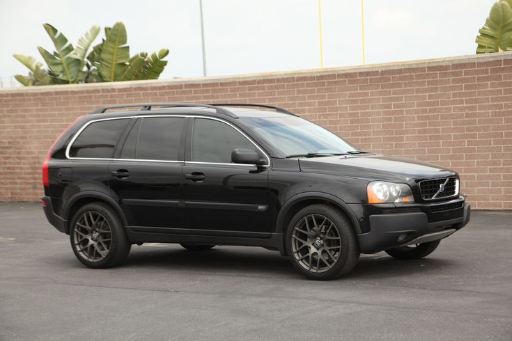 a black suv parked in front of a brick wall