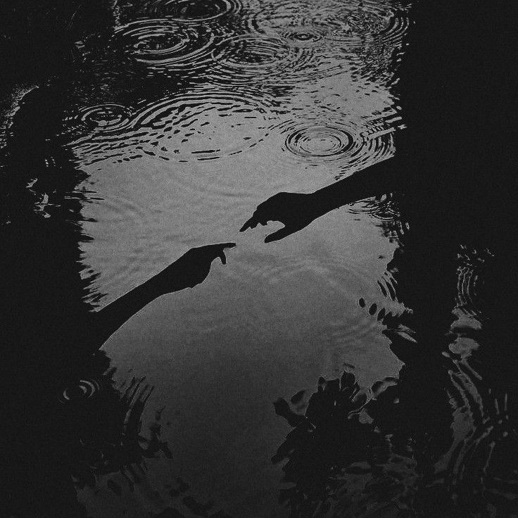 two people reaching out to touch each other's hand while standing in the water