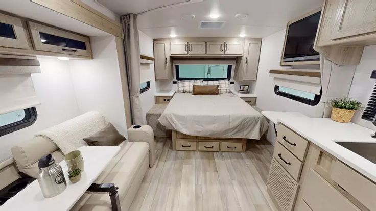 the interior of a travel trailer with a bed, couch and kitchen area in it