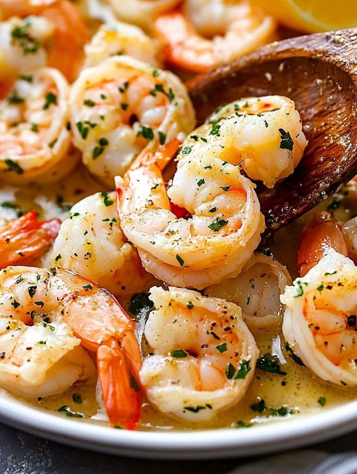 a white bowl filled with shrimp and garnished with parsley on the side