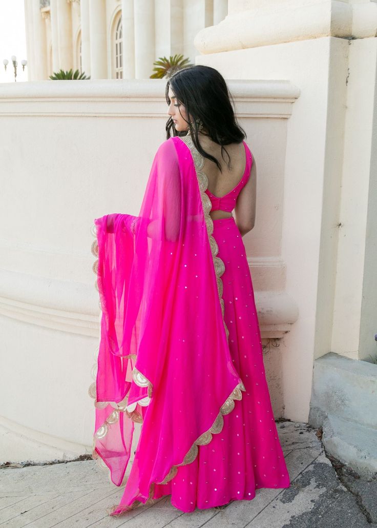 Make a statement with the Tara Lehenga! This bright pink mirror lehenga will add a pop of color to your event. With wedding season around the corner, bright and colorful lehengas are always the right choice! Blouse, skirt, and dupatta included. Pink Anarkali Set With Gota Work For Reception, Pink Dress With Cutdana For Reception, Pink Reception Dress With Cutdana Details, Designer Maxi Length Choli With Mirror Work, Designer Wear Maxi Length Choli With Mirror Work, Bollywood Style Maxi Sharara With Gota Work, Bollywood Style Maxi Length Sharara With Gota Work, Maxi Length Lehenga With Gota Work For Eid, Traditional Maxi Length Lehenga With Gota Work