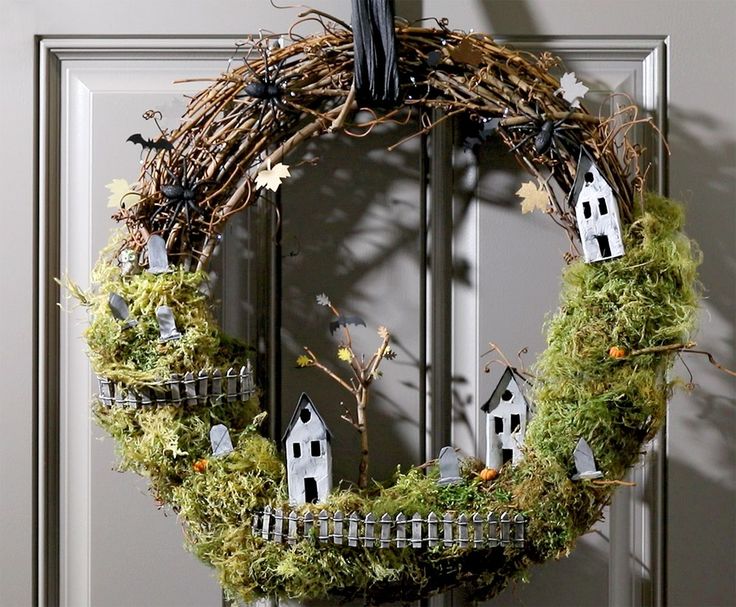 a wreath is hanging on the front door with little houses and trees around it,