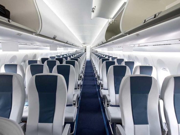 the inside of an airplane with rows of empty seats and blue carpeted flooring