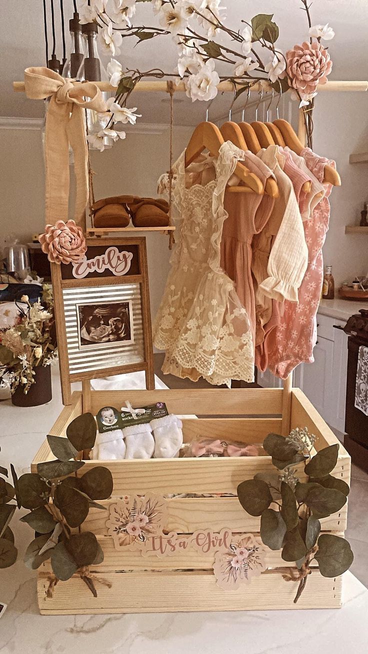 an open wooden box with clothes hanging from it's sides and flowers in the background