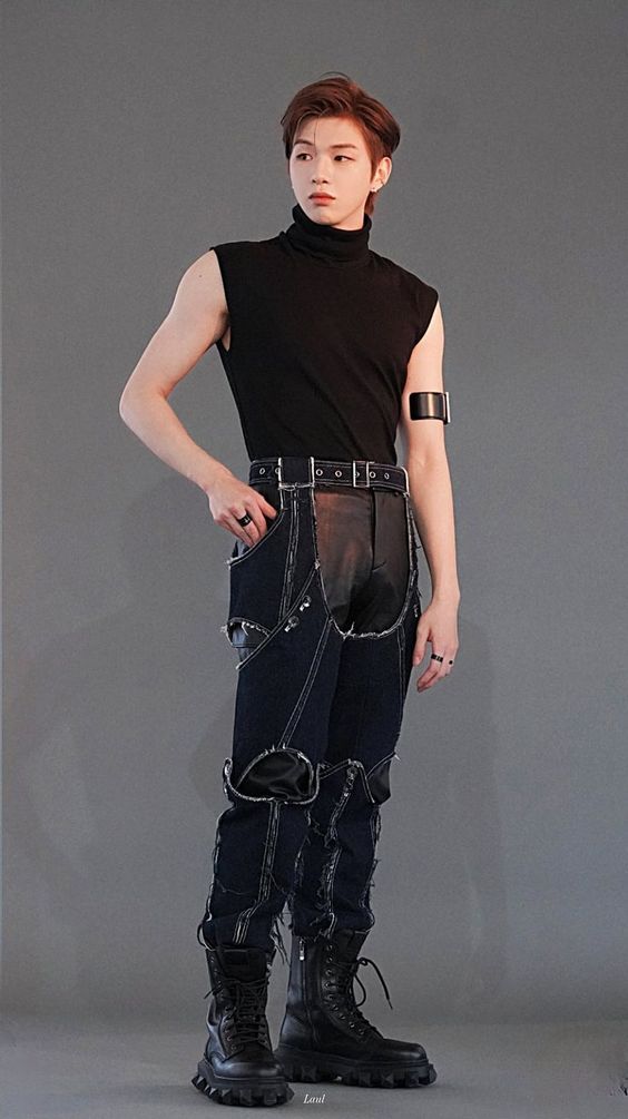 a man standing with his hands on his hips wearing black leather pants and knee high boots