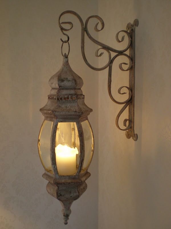 an old fashioned light hanging from the side of a wall next to a candle holder