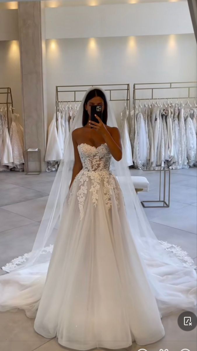 the woman is taking a selfie in her wedding dress while looking at her phone