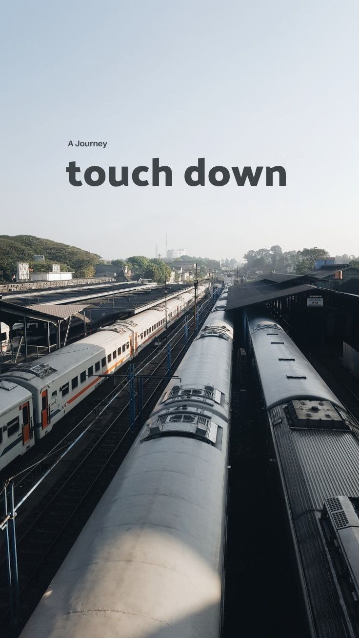 there are many trains that are on the tracks in this city area, and one is white with black lettering