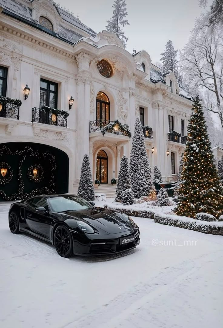 a black sports car parked in front of a large white house with christmas trees and lights