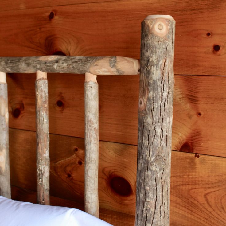 a wooden bed frame with white pillows and wood planks on the wall behind it