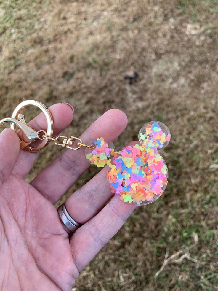 a hand holding a mickey mouse keychain with sprinkles on it