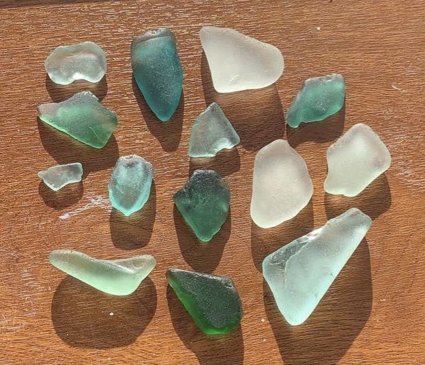 seven pieces of sea glass sitting on top of a wooden table next to each other