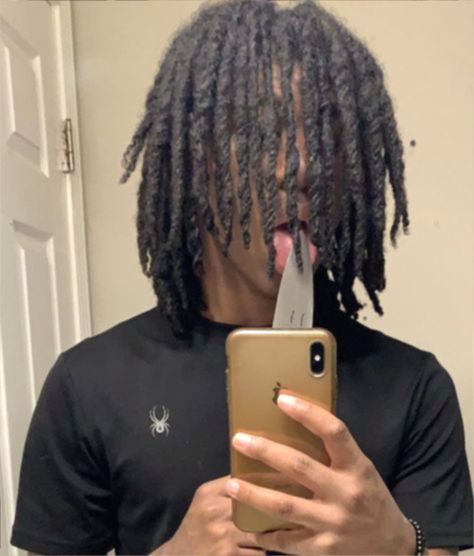 a man with dreadlocks holding an iphone in front of his face