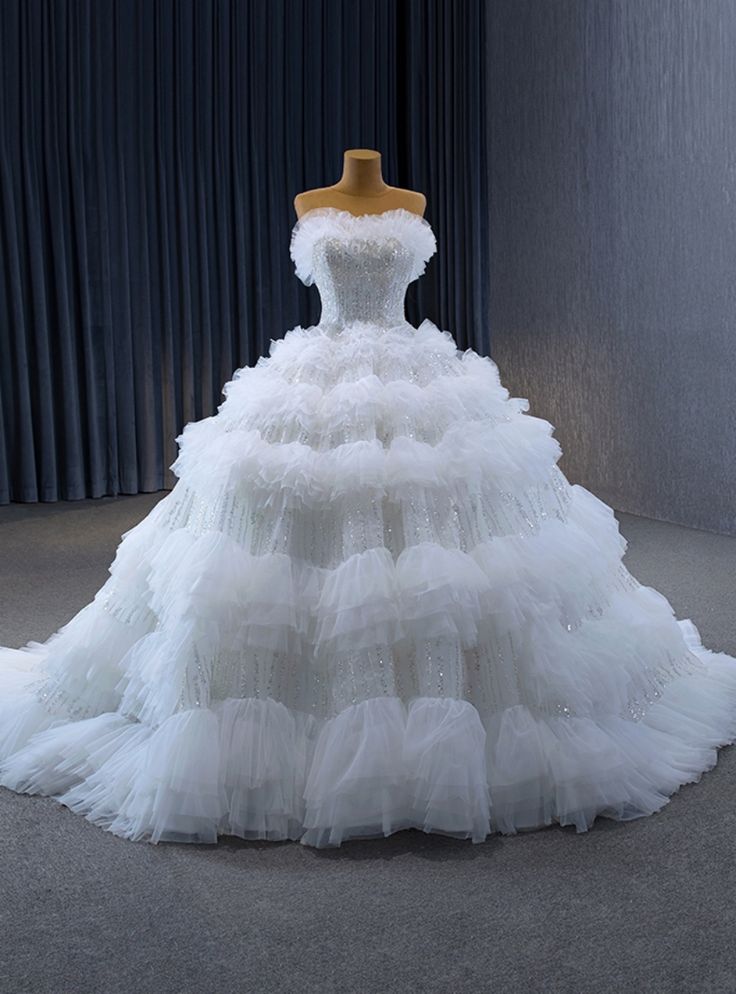 a white wedding dress is displayed on a mannequin headdress in front of a curtain