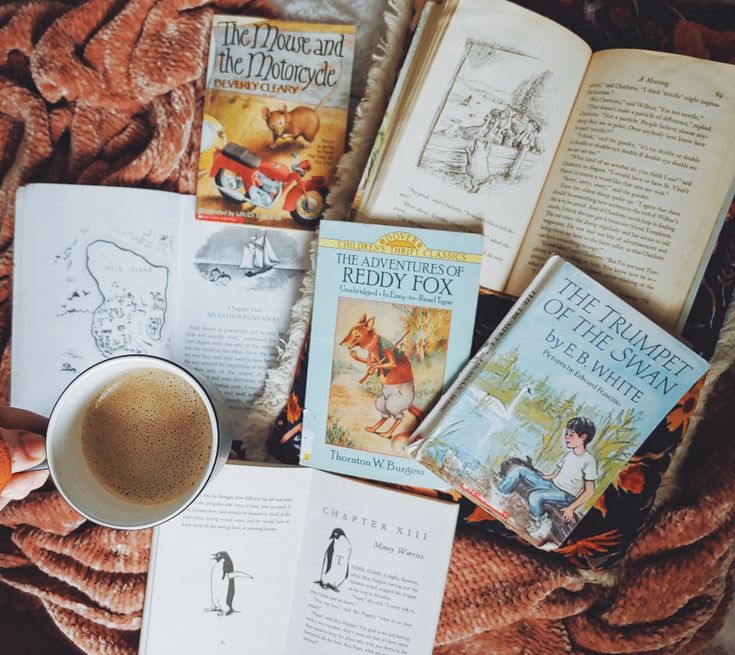 there are many books and coffee on the bed next to each other with an orange cup