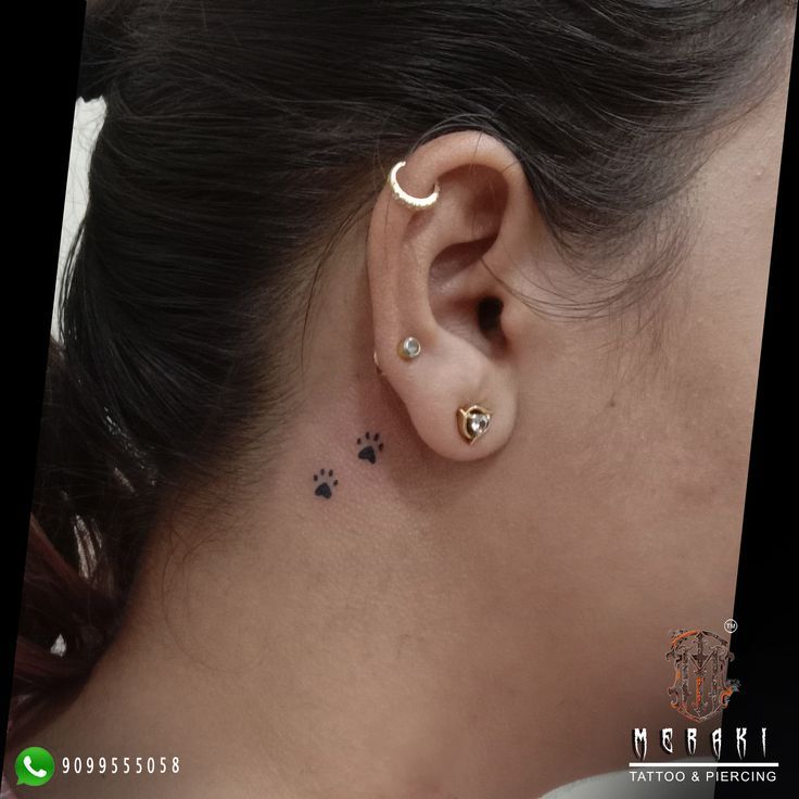 a woman with a small ear tattoo on her left side behind the ear is a dog paw print