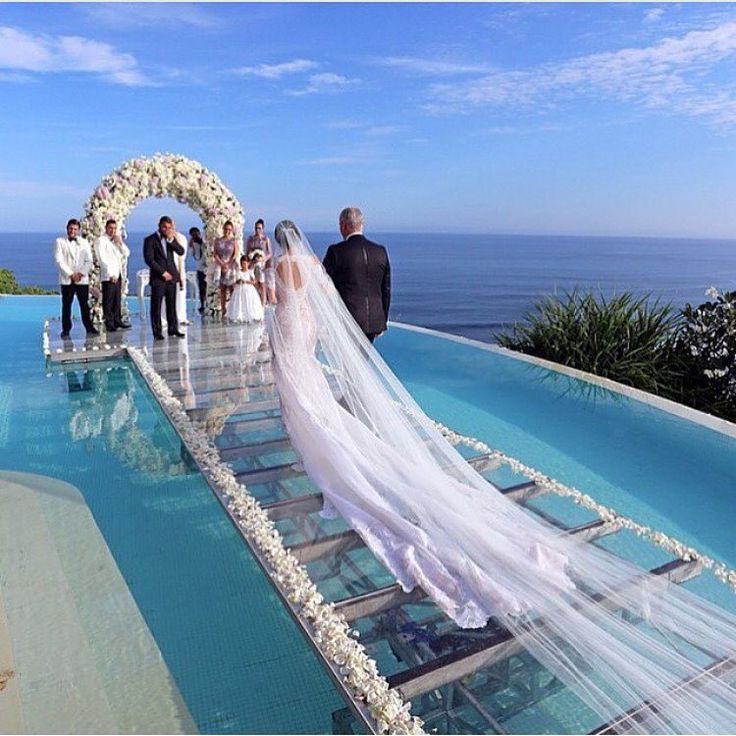 a bride and groom walking down the aisle to their wedding ceremony at an outdoor pool