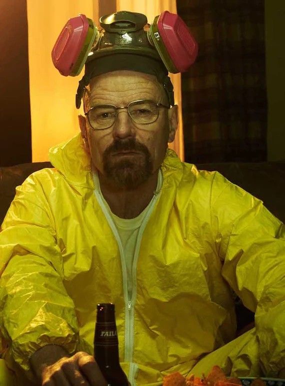 a man in a yellow rain suit holding a beer and looking at the camera while sitting on a couch