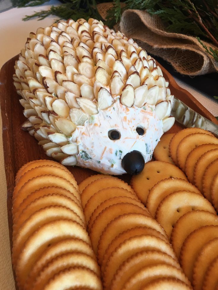 a hedgehog made out of crackers sitting on top of a wooden platter