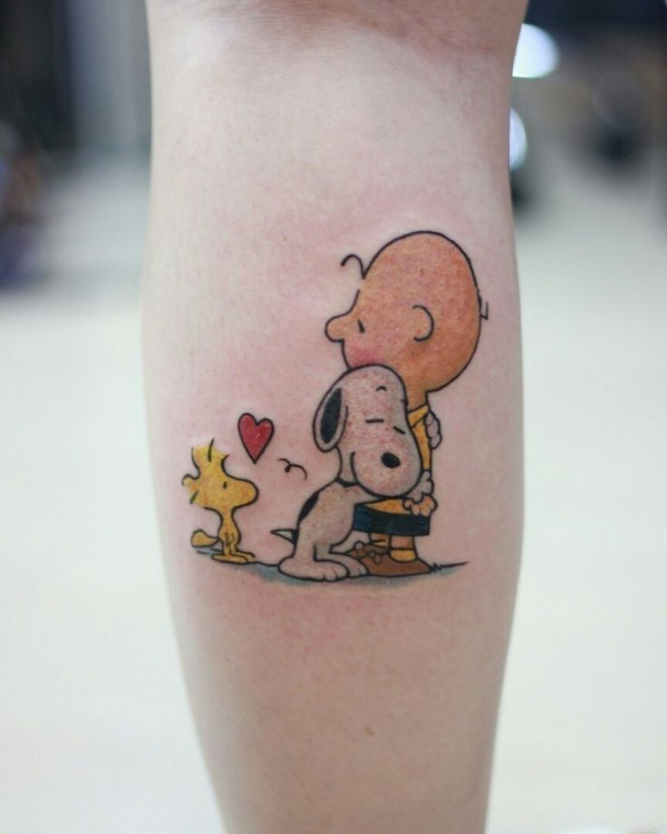 a person with a tattoo on their leg that has a cartoon character holding a dog