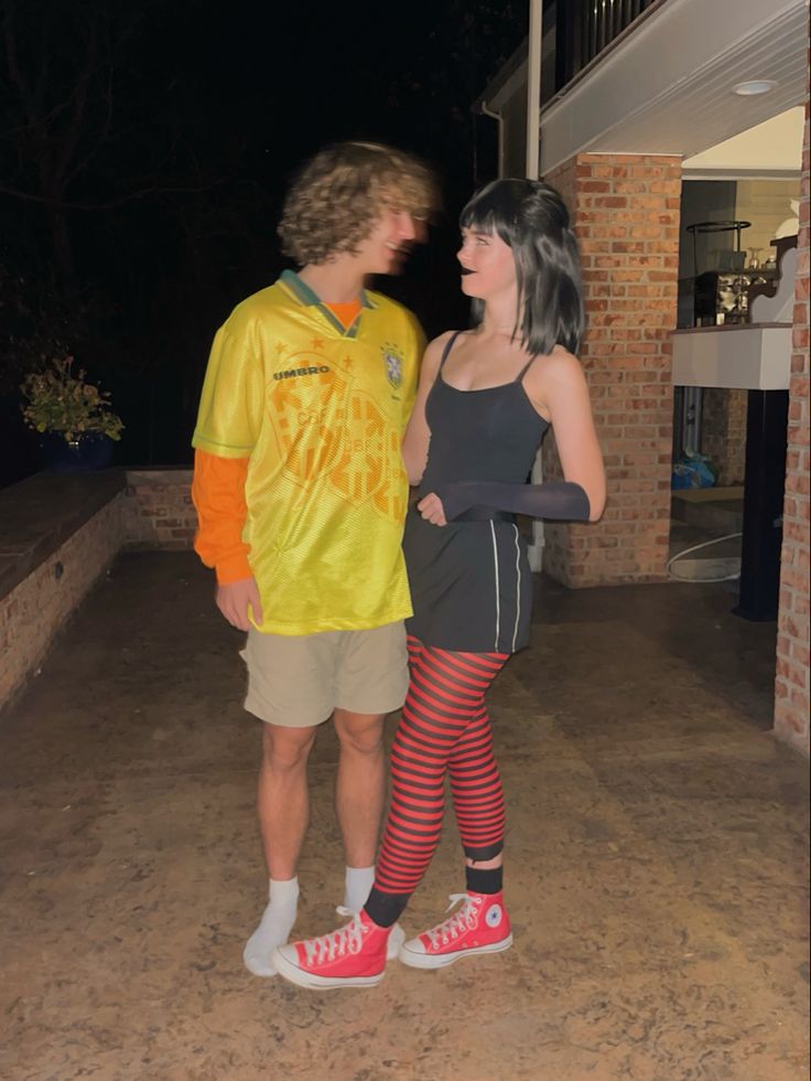 a man and woman standing next to each other in front of a building at night