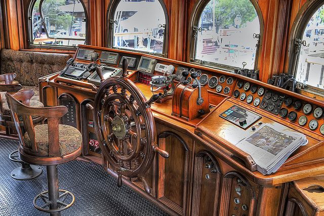 an old fashioned wooden desk and chairs in a room with large round windows on the wall