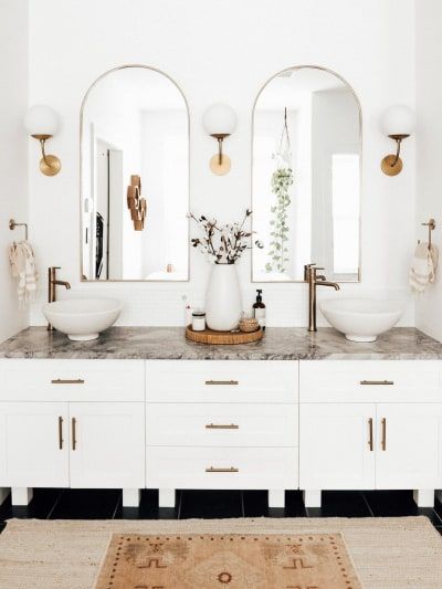 a bathroom with two sinks, mirrors and lights on the wall above it is an area rug