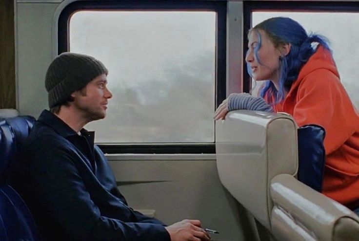 a man and woman sitting on a train next to each other with the words emna icin