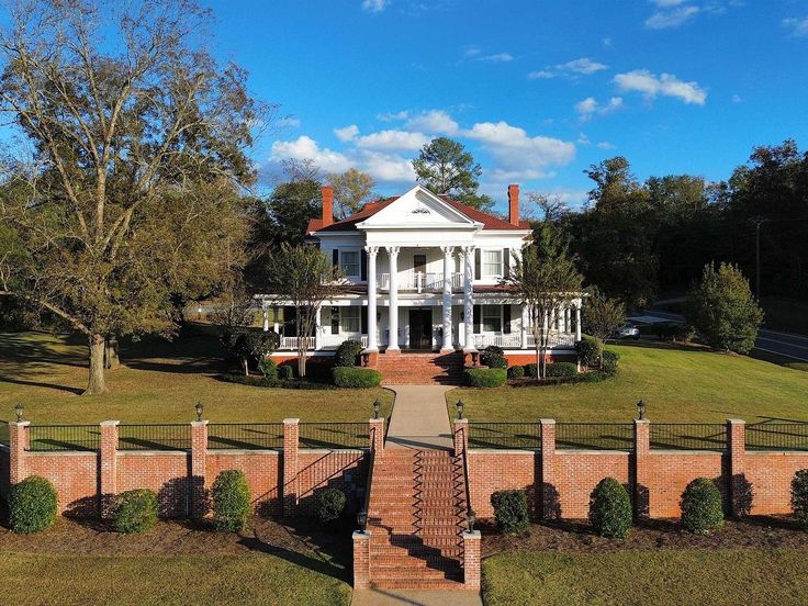 a large white house sitting on top of a lush green field