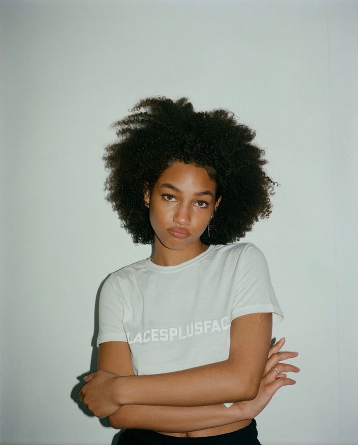 a woman with her arms crossed sitting in front of a white wall