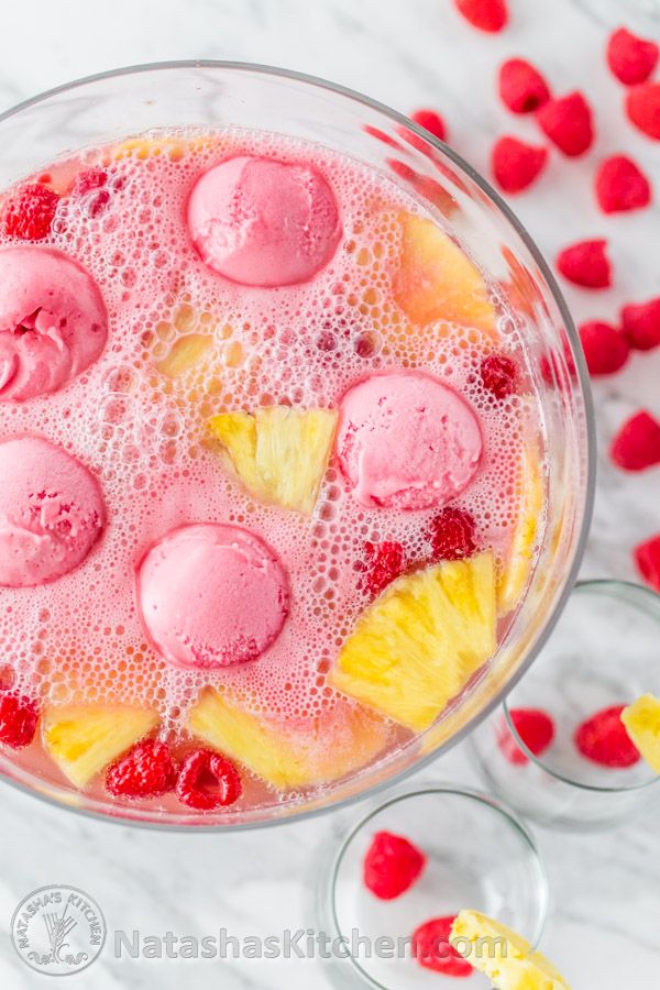 a bowl filled with fruit and ice cream on top of a table next to raspberries