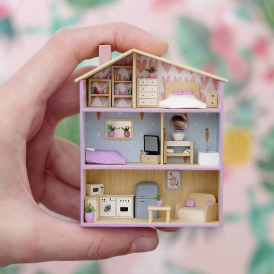 a person holding a doll house in their hand