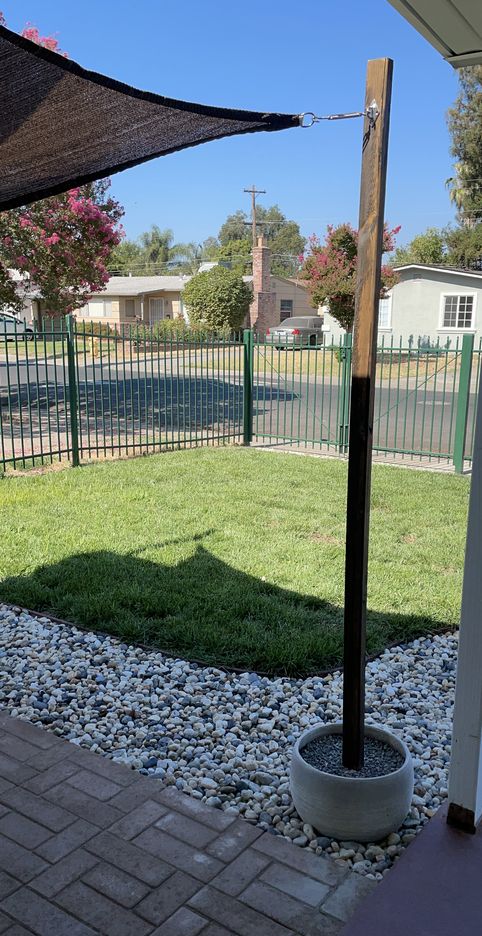 an umbrella is in the middle of a small yard with rocks and gravel on it