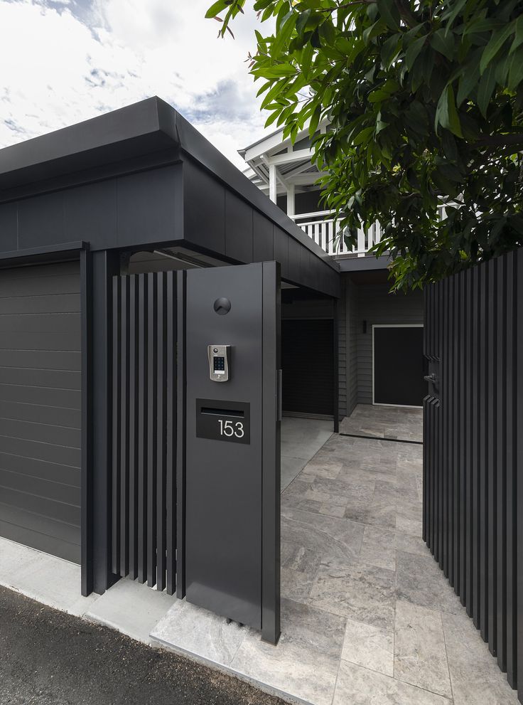 an open garage door in front of a black fence and building with white balconies