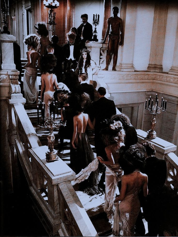 a group of people standing on top of a staircase next to each other in formal dress