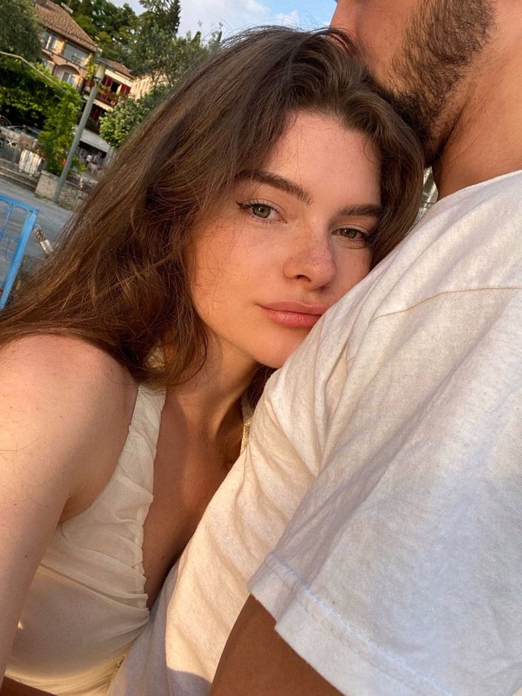 a man and woman sitting next to each other on a bench in front of a swimming pool