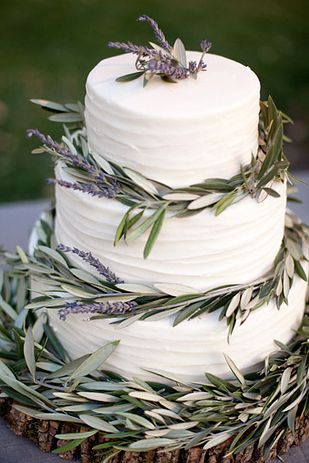 a white wedding cake with greenery on top