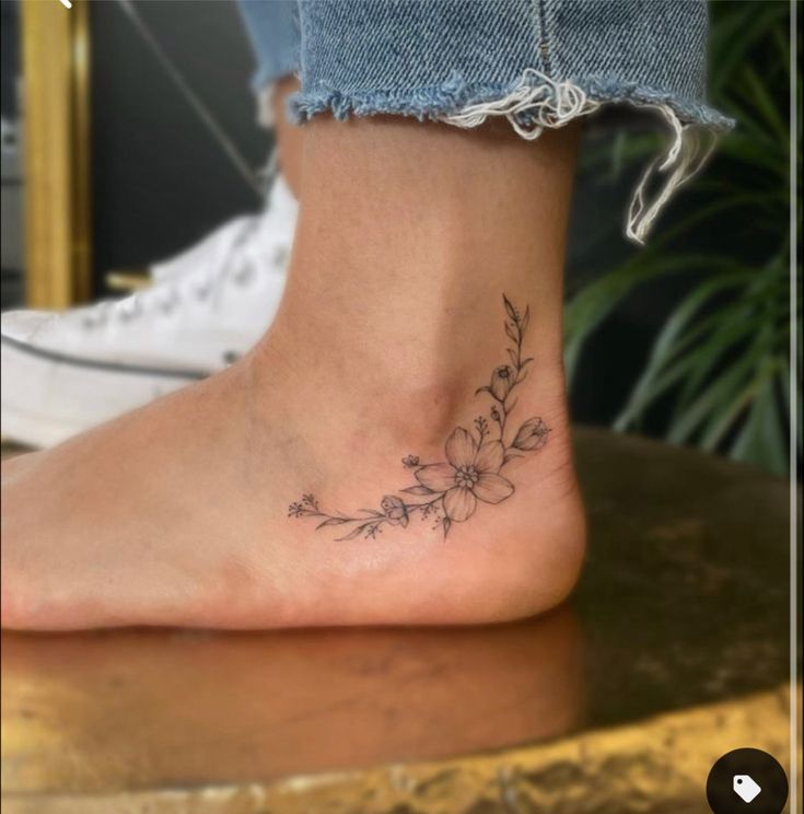 a woman's foot with a small flower tattoo on the side of her ankle