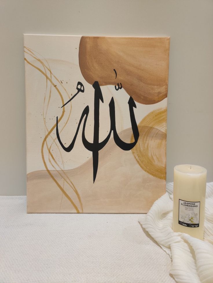 a candle sits next to a painting with the word up written in arabic on it